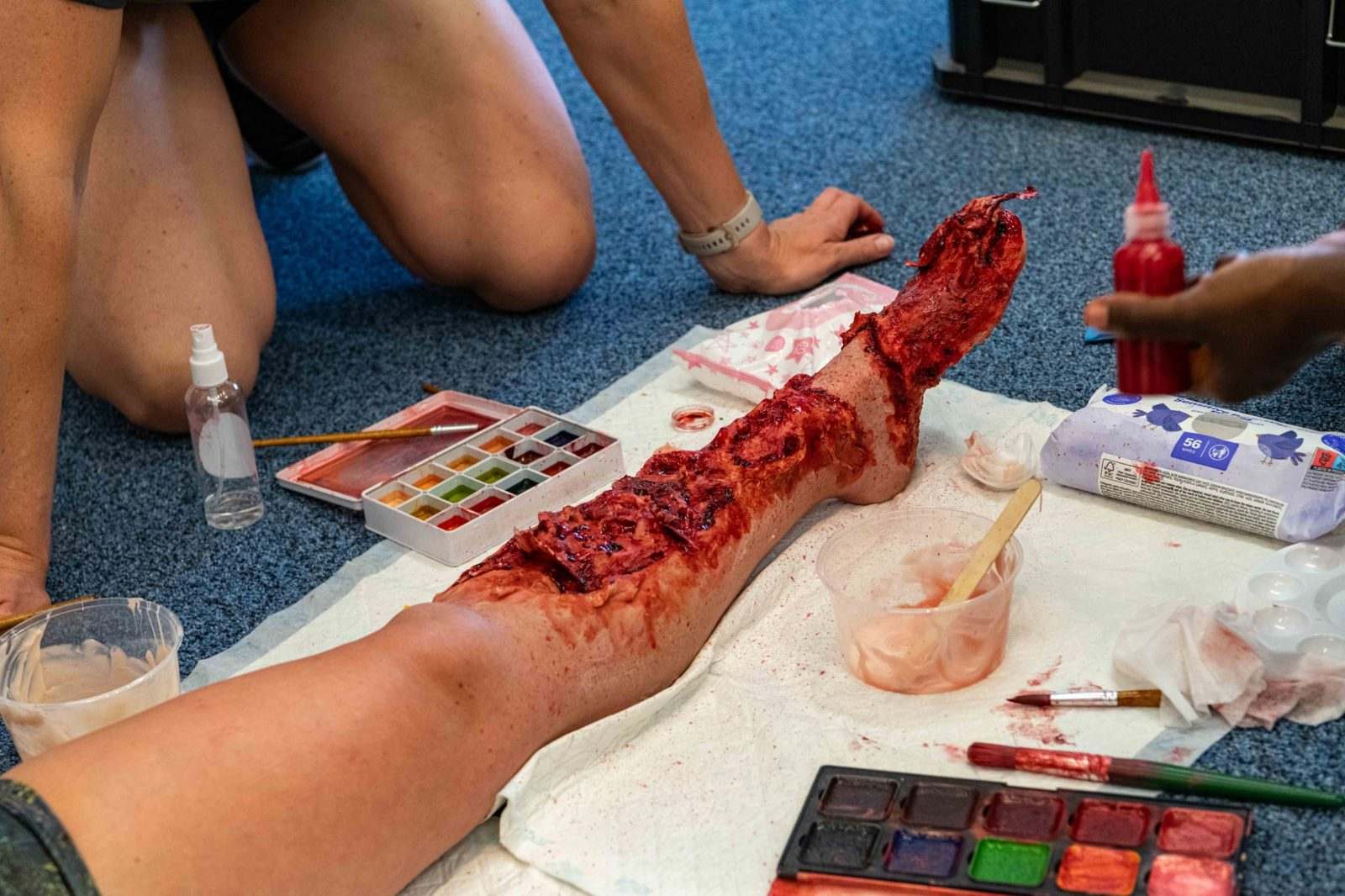 A full-length leg build laid out during a training session, with palettes, brushes and materials around it