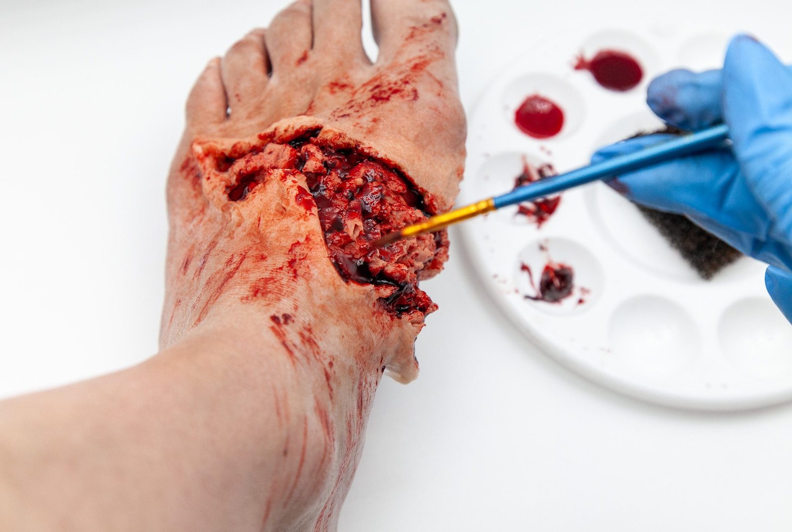 A foot wound being built with a brush, beside a palette of blood colours